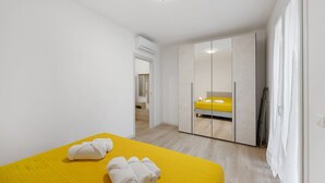 Habitación de hotel con cama, armario y baño visible a través de una puerta abierta.
