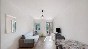 Una habitación moderna y bien iluminada con un sofá, un televisor y una mesa de comedor.