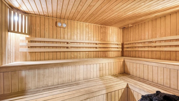 A sauna with wooden benches and a black trash bin. - Las Condes Urban Apartment W/ Wifi and Pool (Las Condes)
