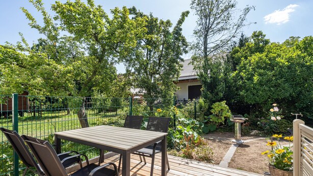 An outdoor patio with a table and chairs, surrounded by a garden with various plants and flowers. - Apartment 'Beim Häusler' with Wi-Fi (Radibor)