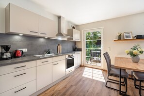 Une cuisine moderne équipée d’un four encastré, d’une machine à café et d’un coin repas avec une table et des chaises.