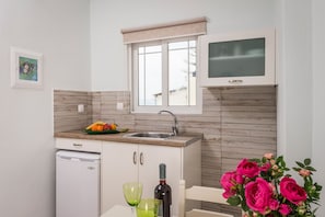 A compact kitchen with a sink, a small refrigerator, and a window with a view.