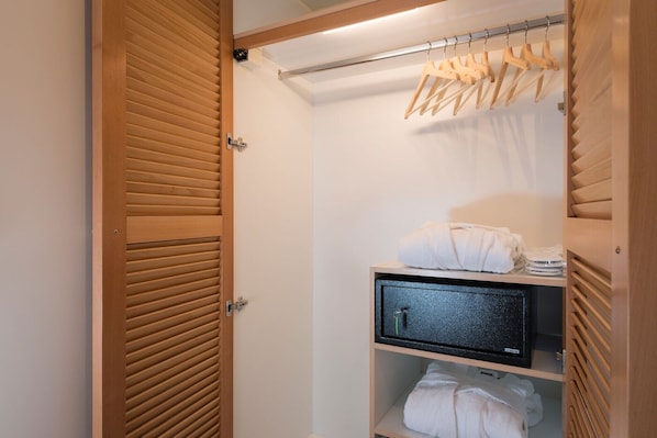 A walk-in closet with wooden sliding doors, a hanging rack, and shelves with folded towels.