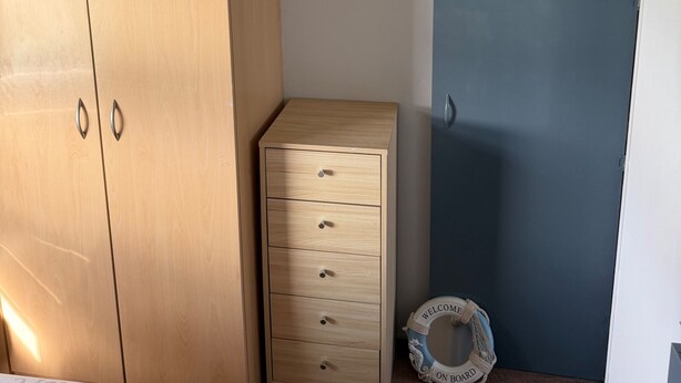 A bedroom with a bed, a wooden wardrobe, a small dresser, a blue door, and a welcome mat on the floor. - Beautiful 3 Bed, Sleeps 6, Wifi, Pet Friendly (Bridlington)