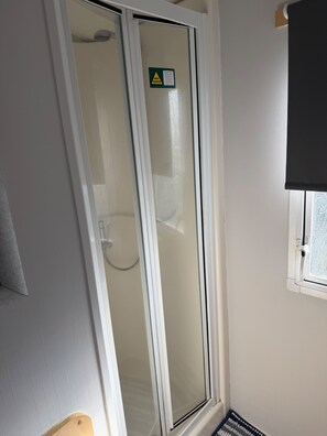 Un baño con mampara de vidrio, un perchero y una ventana con vistas.