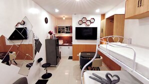 A compact, well-lit room with a bunk bed, a small kitchenette, a dining area, and a TV mounted on the wall. - Cozy Studio Near Clark International Airport, Philippines (Mabalacat City)