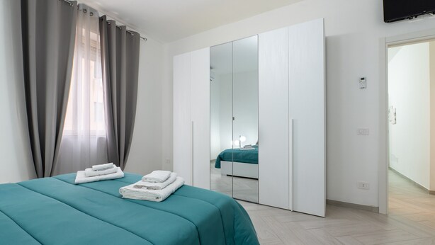 Ein Hotelzimmer mit Bett, Kleiderschrank, Spiegel und Fernseher.