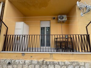 Un balcon avec une rambarde en métal, une porte et un appareil de climatisation.