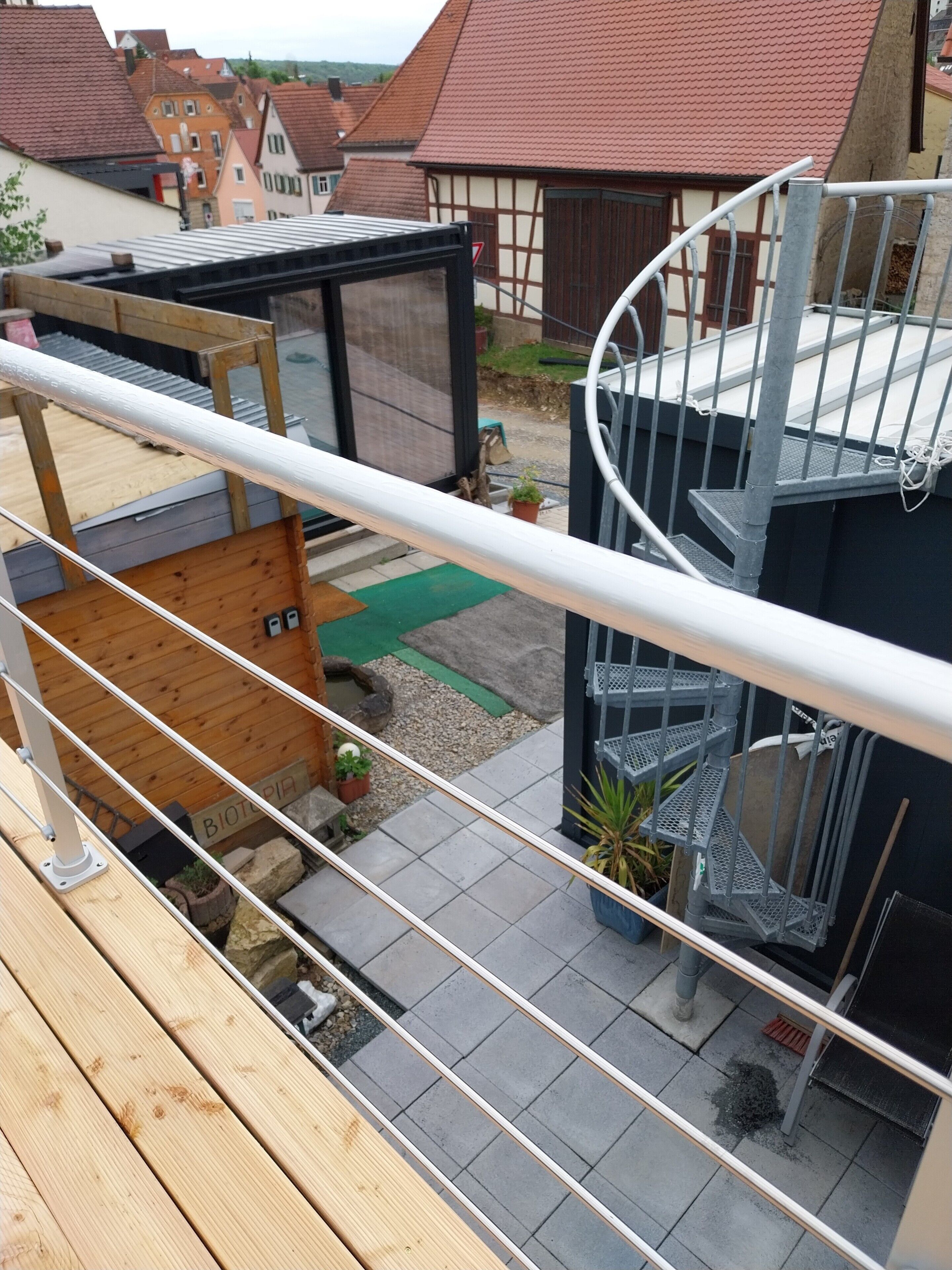 A modern building with a spiral staircase, a wooden deck, and a small garden area.