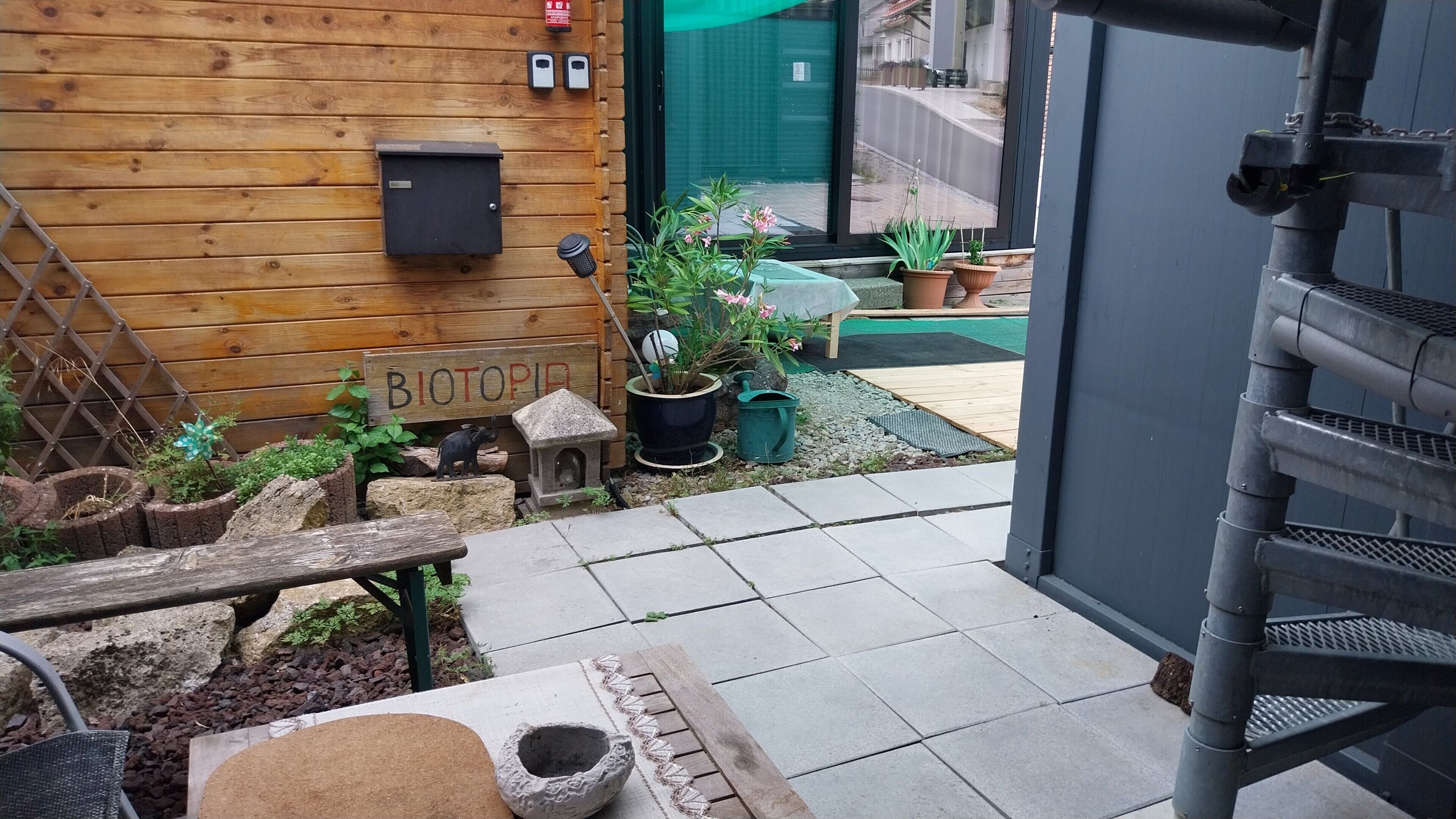 Un mur en bois avec une boîte aux lettres, un banc et des plantes en pot.