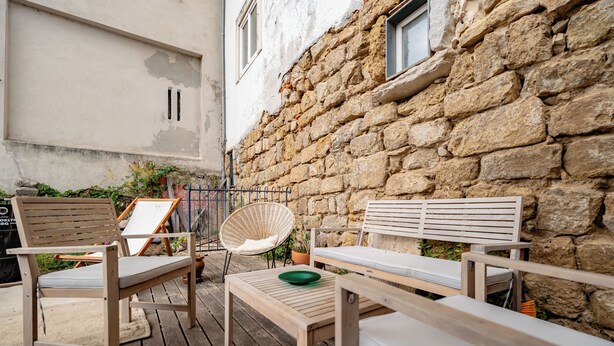 An outdoor seating area with wooden furniture, a stone wall, and a potted plant. - The Balcony of Time - archaeology and history - charming central place wth terrace (Coimbra)