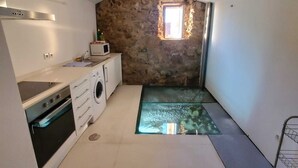 A compact kitchen with a washing machine, a microwave, and a stove. There's a small window with a view of the outside. - The Balcony of Time - archaeology and history - charming central place wth terrace (Coimbra)