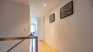 A hallway with wooden flooring, white walls, and two framed artworks. - The Balcony of Time - archaeology and history - charming central place wth terrace (Coimbra)