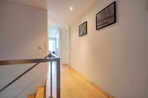 A hallway with wooden flooring, white walls, and two framed artworks. - The Balcony of Time - archaeology and history - charming central place wth terrace (Coimbra)