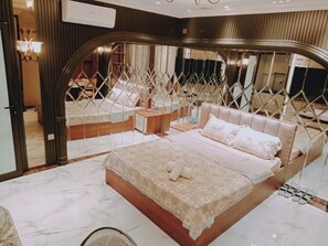 Un dormitorio moderno con una cama grande, un área de descanso separada y un separador metálico decorativo.