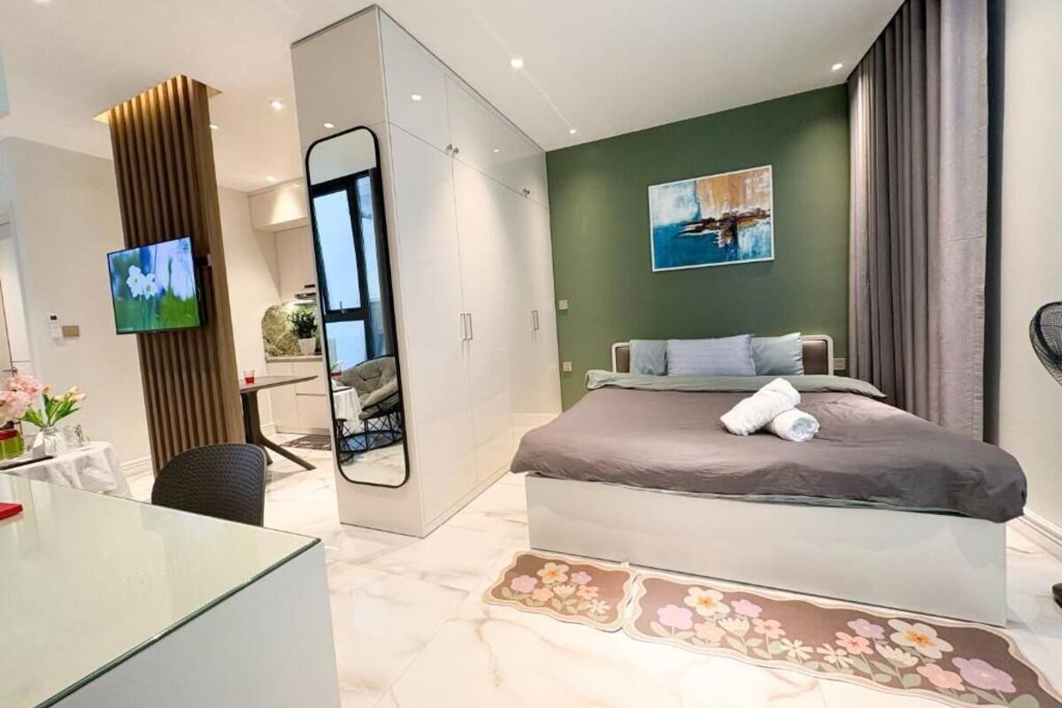 Une chambre d’hôtel moderne équipée d’un lit, d’un bureau, d’un miroir et d’une télévision.