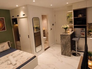A modern bedroom with a bed, a bathroom, and a kitchenette. - GAIA House Kim Ma (Hanoi)