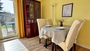 Un comedor con una mesa lista para dos personas, un armario de madera y un cuadro en la pared.