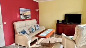 Una sala de estar con un sofá, una mesa de centro, un televisor y un aparador.