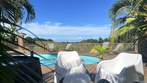Ein Poolbereich mit weißen Liegestühlen und einer Holzterrasse.
