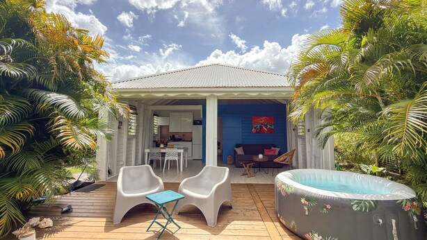 Ein überdachter Außenbereich mit Pool, Sitzgelegenheiten und einer durch eine offene Tür einsehbarer Küche.