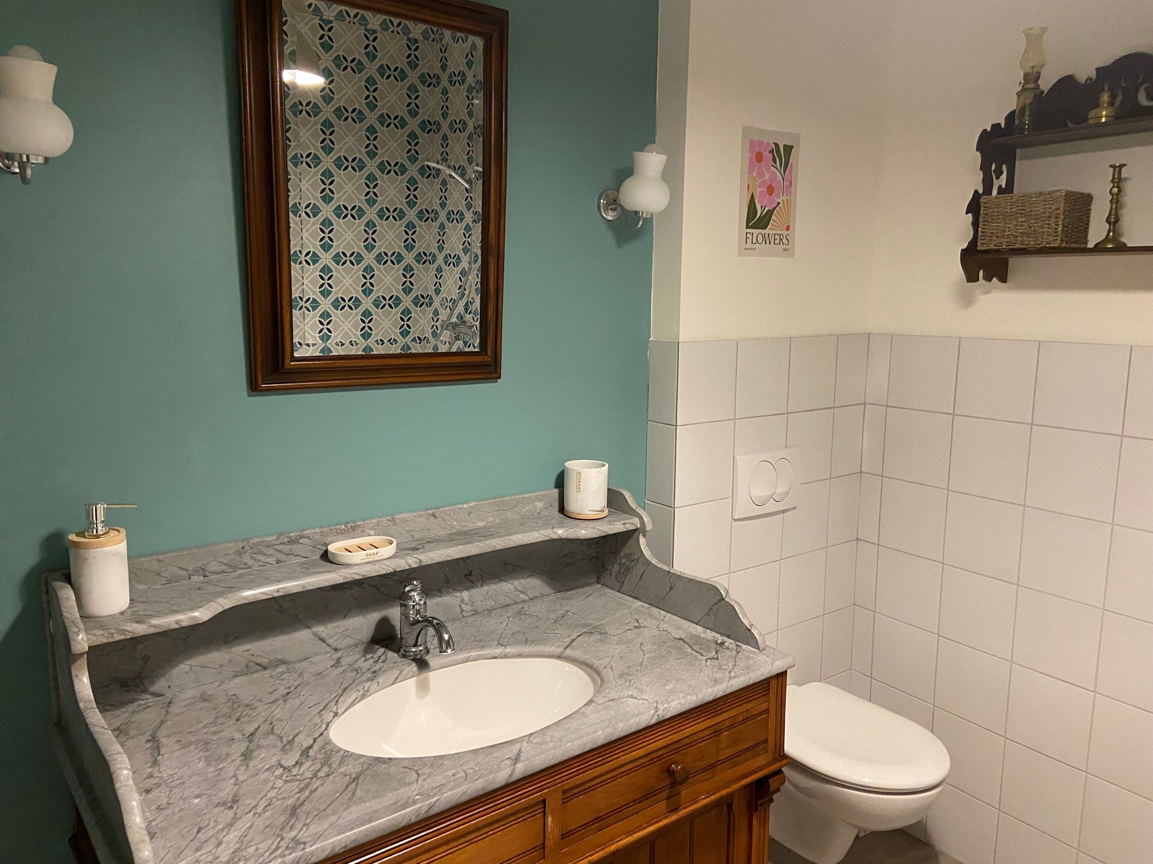 Un bagno con un lavabo in marmo, un water e uno specchio fissato alla parete.