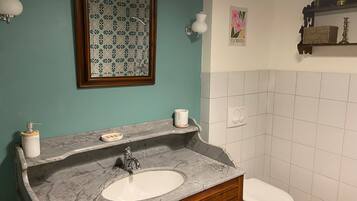 Un bagno con un lavabo in marmo, un water e uno specchio fissato alla parete.