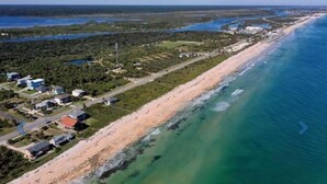 An aerial view of a coastal area with a beach, buildings, and water bodies.
