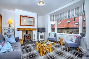 Ein gemütliches Wohnzimmer mit Kamin, Fernseher und einem Karokarpett.