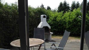 En uteplats med ett runt bord, två stolar och en grill.