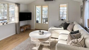 A living room with a sofa, a coffee table, and a TV mounted on the wall. - 5 Star Holiday Home in Farjestaden (Farjestaden)
