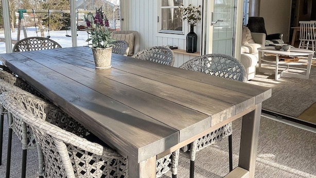A wooden dining table with wicker chairs, a wicker bench, and a hanging light fixture. - 5 Star Holiday Home in Farjestaden (Farjestaden)
