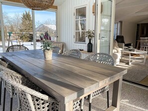 Une table à manger en bois, des chaises en osier, un banc en osier et un luminaire suspendu.