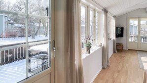 A room with large windows, a wooden floor, and a television. - 5 Star Holiday Home in Farjestaden (Farjestaden)