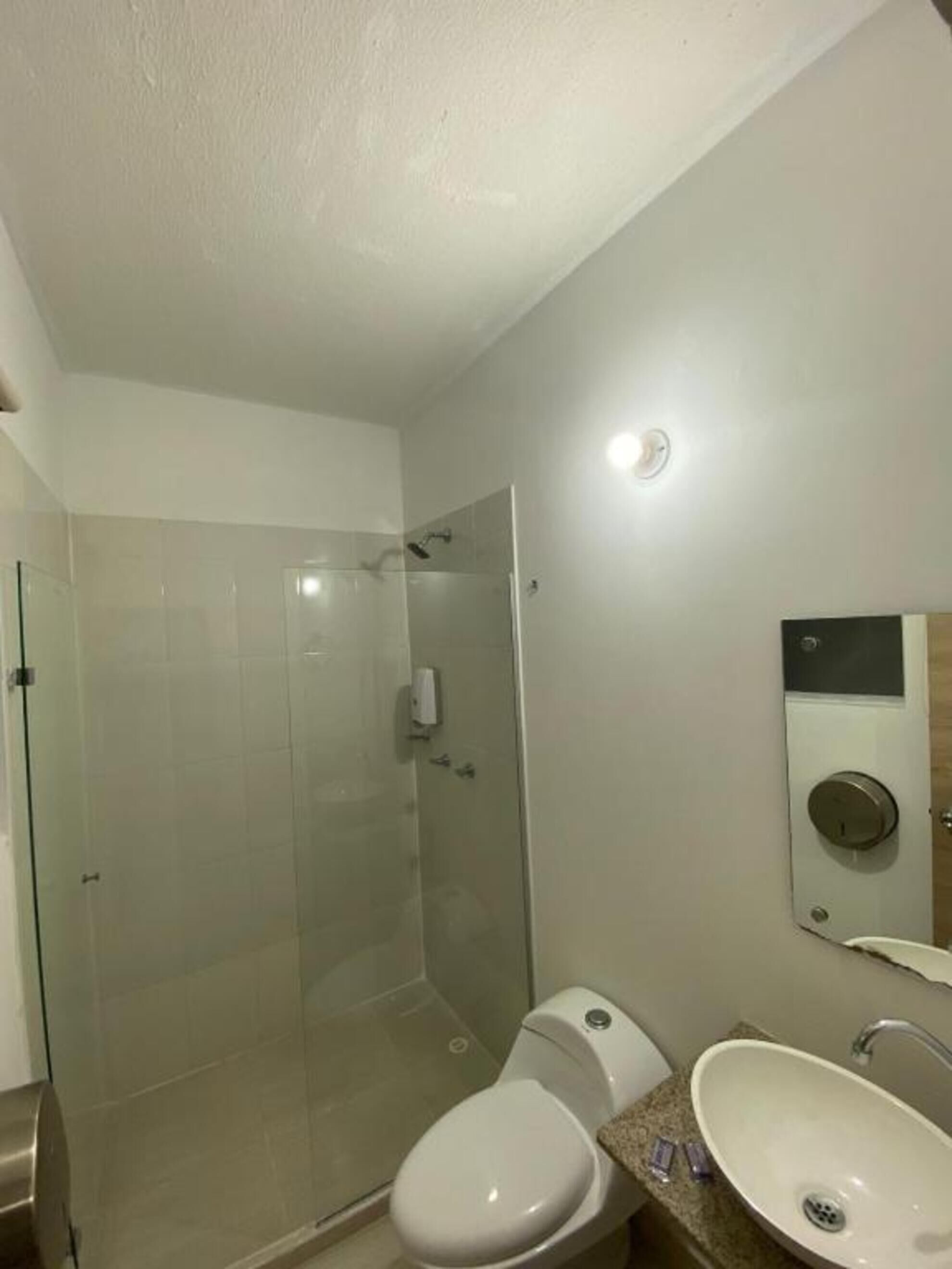 A modern bathroom with a glass shower enclosure, a toilet, and a sink.