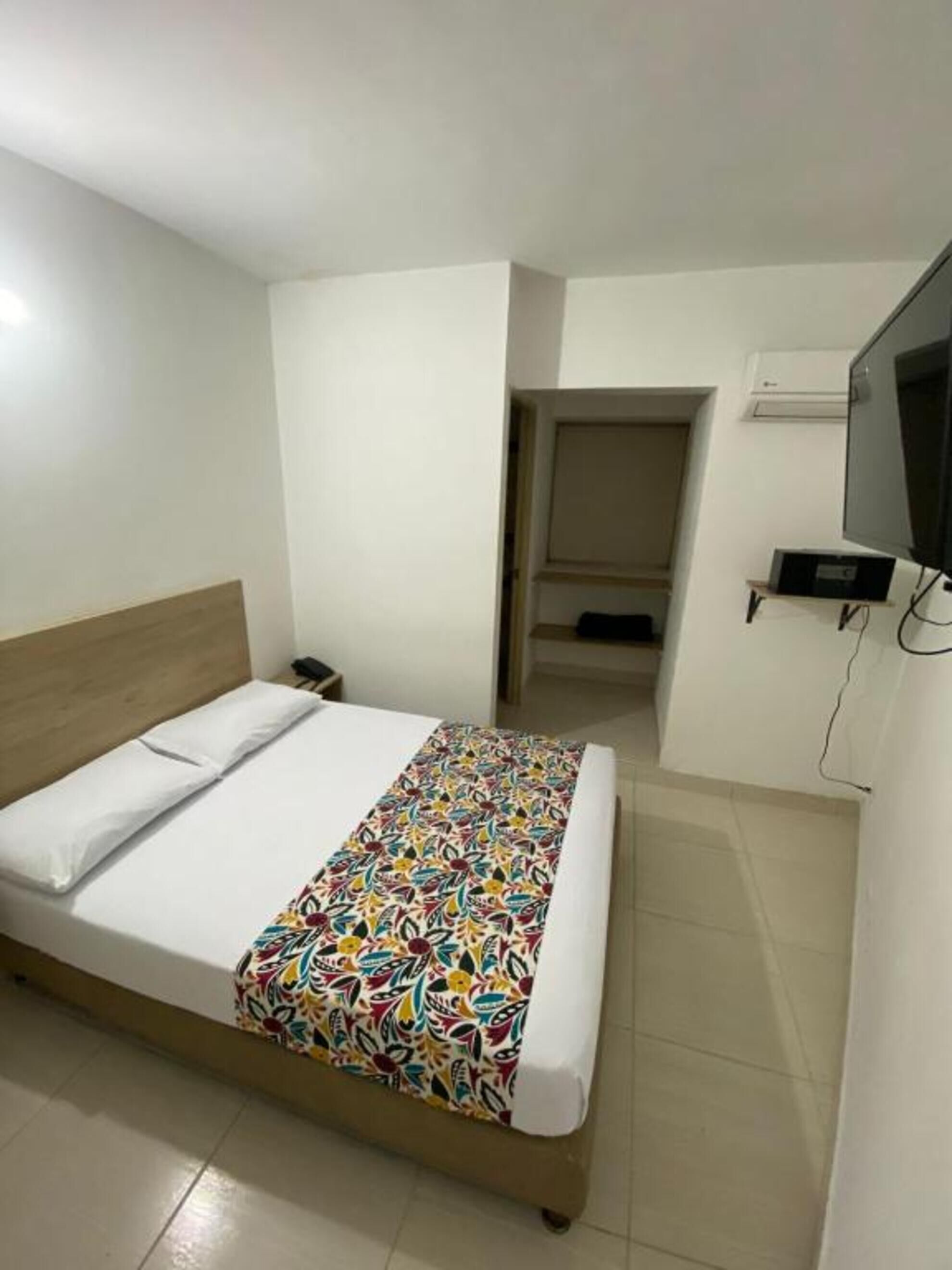 A hotel room with a bed, a TV, and a door leading to another room.