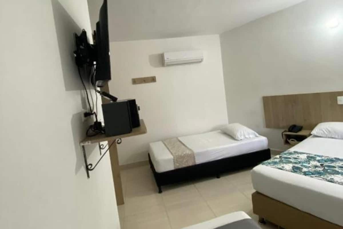 Een hotelkamer met twee bedden, een aan de muur bevestigde televisie en een airconditioning.