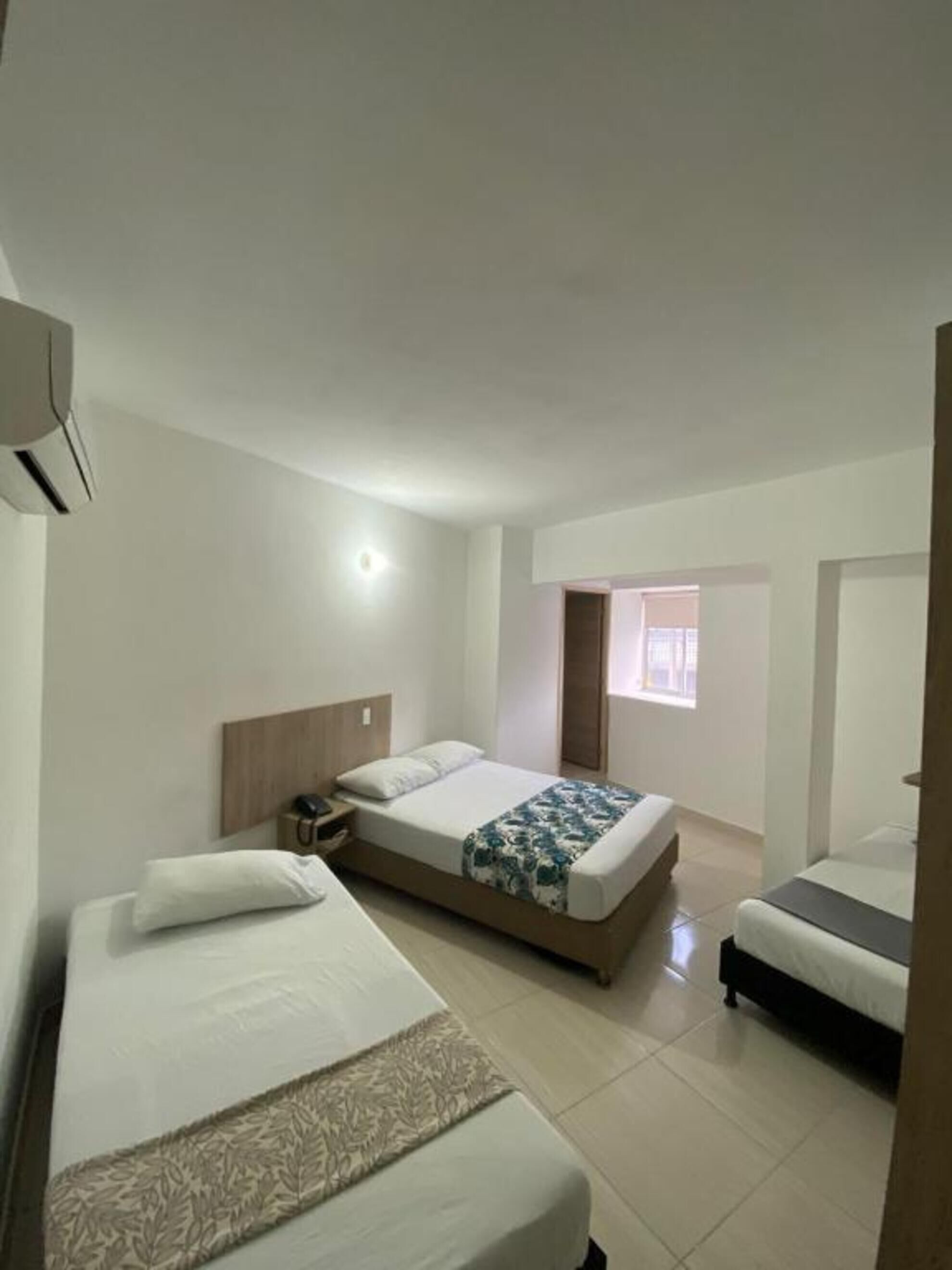 A hotel room with a single bed, a bedside table, a nightstand, and a window.
