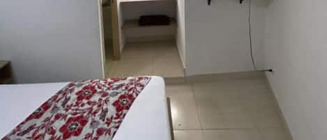 A small, clean room with a bed, a window, and an air conditioning unit.