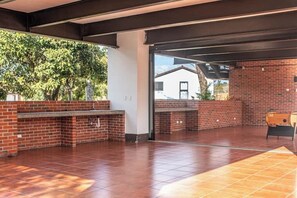 An outdoor patio area with a brick barbecue and a tiled floor.
