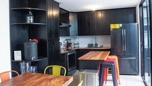 A modern kitchen with dark cabinetry, a wooden dining table, and a refrigerator. - *Beautiful colonial house* in Antigua Guatemala (Alotenango)