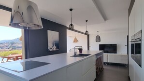 A modern kitchen with a large island, pendant lights, and a view of the countryside. - A beautiful luxury villa in a quiet location 1 km from the beach and town centre (Cavalaire-sur-Mer)