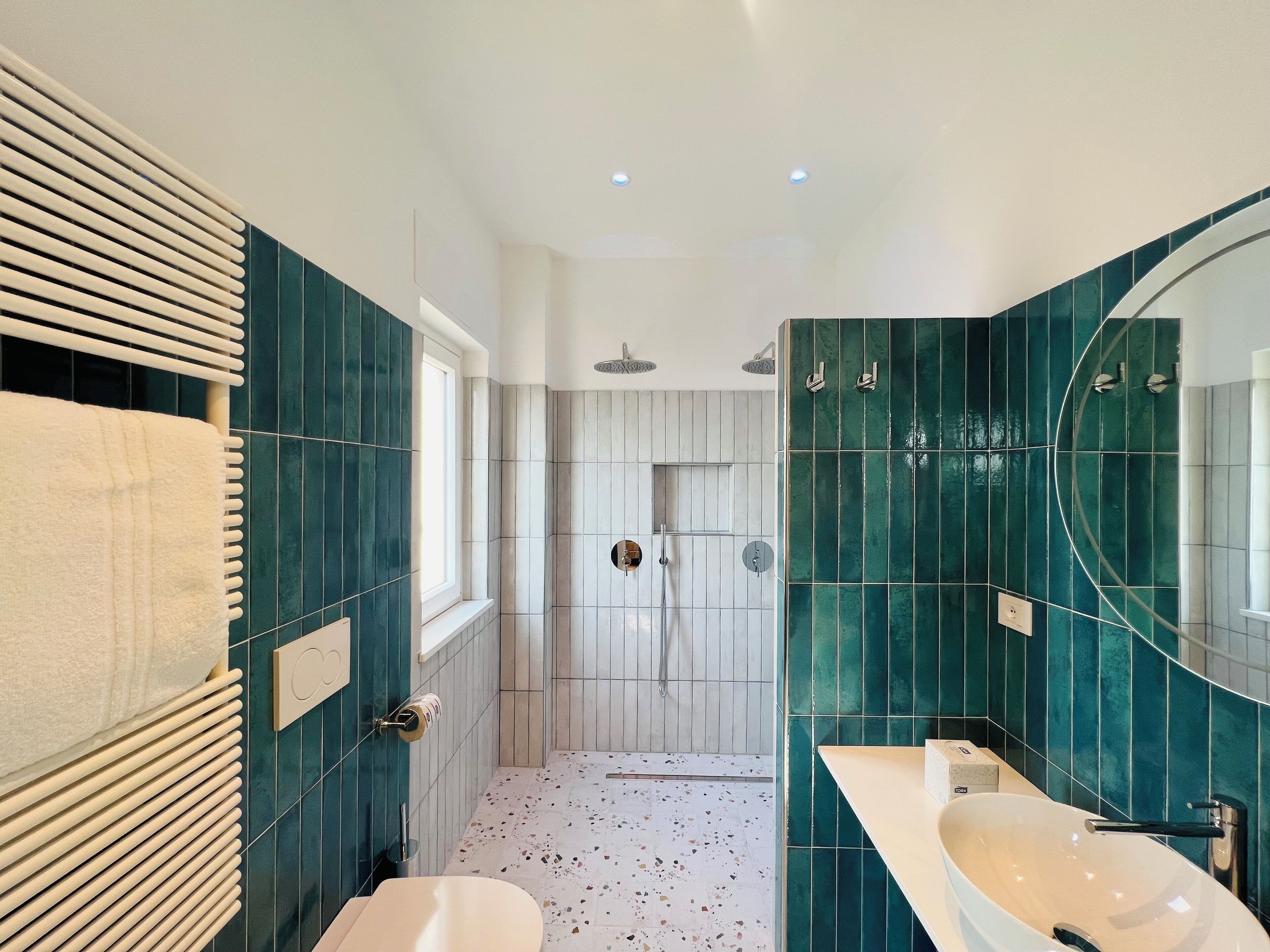 Ein modernes Badezimmer mit freistehender Badewanne, einem großen Spiegel und einer Dusche mit Regendusche.