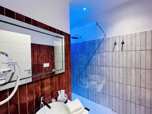 A modern bathroom with a large mirror, a white sink, a handheld showerhead, and a towel rack. - YourHome - Lucrezia Suites (Sorrento)