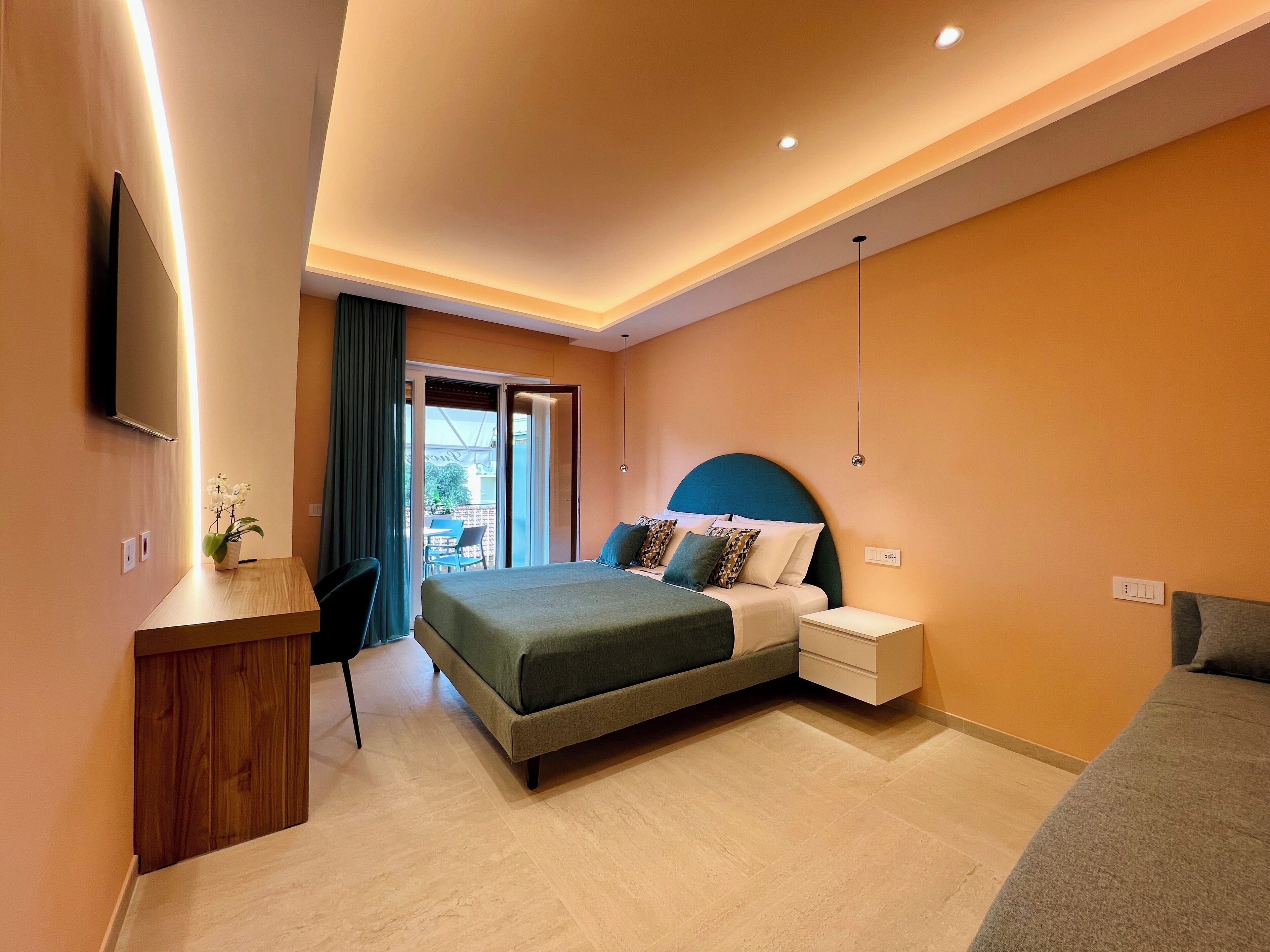 Una camera d'albergo moderna con un letto, comodini, una scrivania e una televisione.