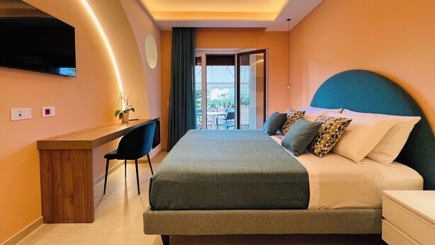 Ein modernes Hotelzimmer mit Bett, Schreibtisch und Blick ins Freie.