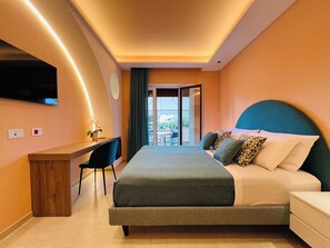 A modern hotel room with a bed, desk, and a view of the outdoor area. - YourHome - Lucrezia Suites (Sorrento)