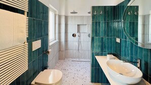 Ein modernes Badezimmer mit freistehender Toilette, einem großen Spiegel und einer Badewanne.
