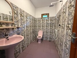 Un baño con inodoro, lavamanos, ducha y una ventana pequeña.