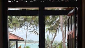 Ein Zimmer mit Blick auf Strand und Palmen.